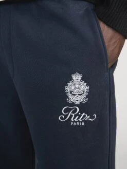 FRAME x Ritz Paris Navy Embroidered Logo Luxury Sweatpants - Essential Cuffed Joggers 14 FRAME x Ritz Paris Navy Embroidered Logo Luxury Sweatpants - Essential Cuffed Joggers -FRAME Clothing Shop LMAC0279 NAVY 02556 SideDetail OnModel
